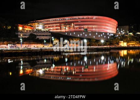 Nachtaufnahme des San Mamés Stadions in Bilbao. Wunderschöne bunte Reflexionen auf dem Fluss Nervión (Fluss des Baskenlandes). Stockfoto