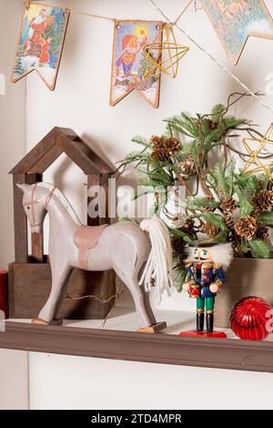 Hölzerne Innendekoration in Form von Häusern mit einer Nussknacker-Figur und einem eleganten Hirsch auf dem Hintergrund von Weihnachtsbaumzweigen in einem Sho Stockfoto