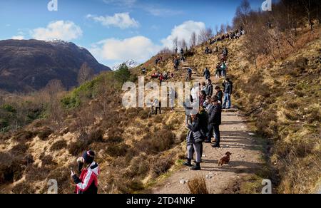 Touristen, die darauf warten, die Dampfeisenbahn Jakobiten über den Glenfinnan Viaduct in Highlands, Schottland, zu sehen. Berühmt durch die Harry-Potter-Filme. Stockfoto