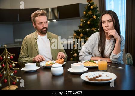 Trauriger Mann und Frau beim Neujahrsfrühstück, traurig nach dem Streit Stockfoto