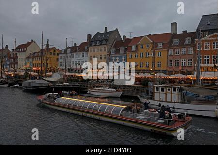 In der Abenddämmerung als Teil des Julemark (Weihnachtsmarkt) beleuchtet ist die Uferpromenade von Nyhavn aus dem 17. Jahrhundert mit ihren vertäuten Booten und einer großen Anzahl von Restaurants Stockfoto