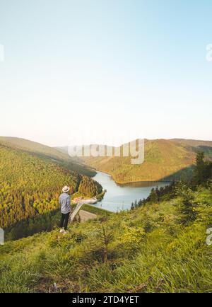 Mann in Hemd und Hut, der den Sonnenuntergang beobachtet, der Sance Damm, Ostravice, Beskiden Berge, Tschechien. Die bezaubernde Natur Mitteleuropas. Stockfoto