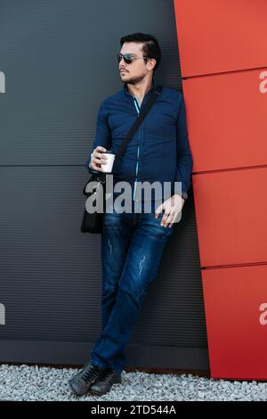 Ein junger Mann trinkt draußen einen Kaffee zum Mitnehmen Stockfoto