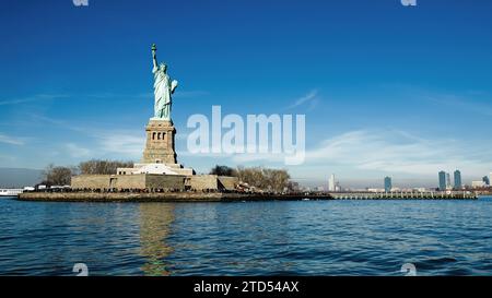 Die Freiheitsstatue steht hoch vor der Kulisse der Skyline von Manhattan und symbolisiert die amerikanische Freiheit. Stockfoto