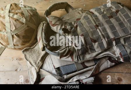 Ein Militärhelm eines ukrainischen Soldaten mit einer schweren kugelsicheren Weste auf einem Holztisch im Innenraum des Kontrollpunktes Stockfoto