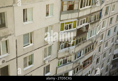 Fassade eines grauen mehrstöckigen sowjetischen Paneelgebäudes. Russische alte urbane Wohnhäuser mit Fenstern und Balkon. Typische russische Nachbarschaft Stockfoto