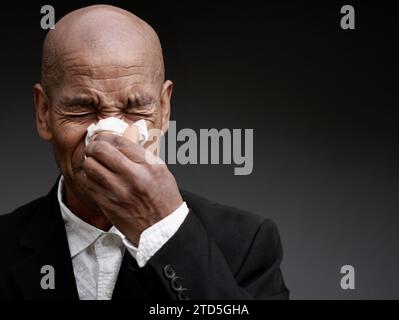 Mann, der die Erkältung und Grippe fängt Mann, der Nase bläst, nachdem er eine Erkältung mit grauem Hintergrund mit Leuten Stock Foto gefangen hat Stockfoto