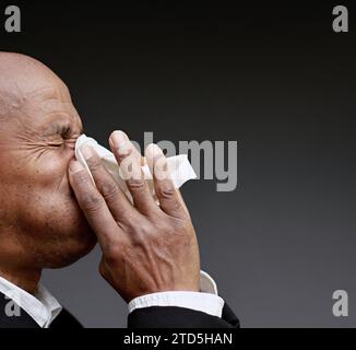 Mann, der die Erkältung und Grippe fängt Mann, der Nase bläst, nachdem er eine Erkältung mit grauem Hintergrund mit Leuten Stock Foto gefangen hat Stockfoto