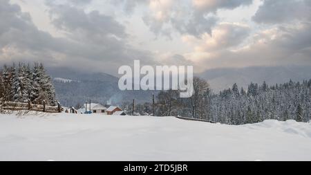 Schneefall über Hügeln, Hainen und Ackerland im Winter abgelegenen alpinen Bergdorf Stockfoto
