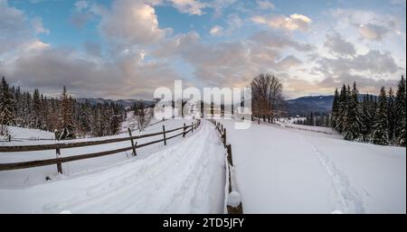 Sekundäre Landschaft alpine Straße in abgelegenen Bergdorf, Schneeverwehungen und Holzzaun am Wegesrand Stockfoto