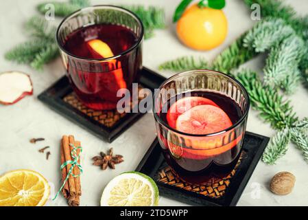 Zwei Gläser mit Glühwein, Sternanis, Zimtstangen, Muskatnuss- und Tannenzweigen auf weißem Tisch. Draufsicht. Stockfoto