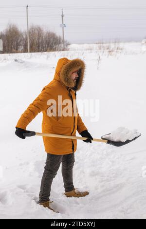 Mann, der Schnee vom Bürgersteig reinigt und Schneeschaufel benutzt. Wintersaison Stockfoto
