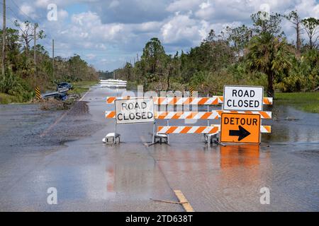 Die Straße in Florida wurde nach Hurrikanregen überflutet, und die Straße wurde durch Schilder gesperrt, die das Fahren von Autos blockieren. Sicherheit des Transports bei Naturkatastrophen Stockfoto