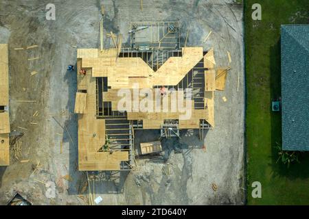 Professionelle Bauarbeiter, die an der Dachkonstruktion eines unvollendeten Vorstadthauses mit Holzrahmenstruktur im ländlichen Gebiet Floridas arbeiten. Wohnungskonzept Stockfoto