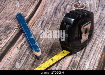 Ein Nahbild eines gelben Zimmermannsbandmaßes und Holzbleistifts. Stockfoto