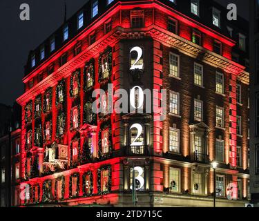 London, Großbritannien. Dezember 2023. Die jährlichen Fortnum & Mason Weihnachtsdekorationen sind hoch und zeigen wieder einmal einen riesigen Adventskalender auf der Fassade, in dem jedes Fenster eine kleine Tür darstellt und die Tage bis Weihnachten herunterzählt. Das Gebäude in Piccadilly ist rot beleuchtet und zieht große Touristenmassen an. Quelle: Imageplotter/Alamy Live News Stockfoto