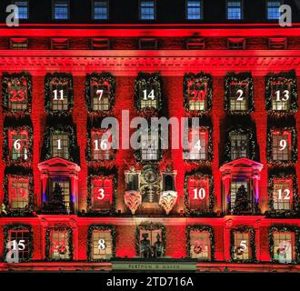 London, Großbritannien. Dezember 2023. Die jährlichen Fortnum & Mason Weihnachtsdekorationen sind hoch und zeigen wieder einmal einen riesigen Adventskalender auf der Fassade, in dem jedes Fenster eine kleine Tür darstellt und die Tage bis Weihnachten herunterzählt. Das Gebäude in Piccadilly ist rot beleuchtet und zieht große Touristenmassen an. Quelle: Imageplotter/Alamy Live News Stockfoto