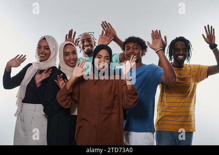 Eine jubelnde und vielfältige Gruppe, darunter ein Afroamerikaner und Hijab tragende Mädchen, winken und feiern überschwänglich und verkörpern die Lebendigkeit von Stockfoto