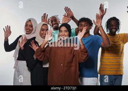 Eine jubelnde und vielfältige Gruppe, darunter ein Afroamerikaner und Hijab tragende Mädchen, winken und feiern überschwänglich und verkörpern die Lebendigkeit von Stockfoto
