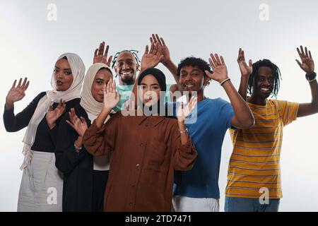 Eine jubelnde und vielfältige Gruppe, darunter ein Afroamerikaner und Hijab tragende Mädchen, winken und feiern überschwänglich und verkörpern die Lebendigkeit von Stockfoto
