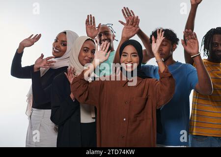 Eine jubelnde und vielfältige Gruppe, darunter ein Afroamerikaner und Hijab tragende Mädchen, winken und feiern überschwänglich und verkörpern die Lebendigkeit von Stockfoto