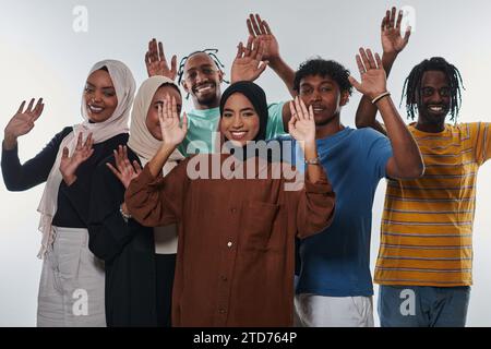 Eine jubelnde und vielfältige Gruppe, darunter ein Afroamerikaner und Hijab tragende Mädchen, winken und feiern überschwänglich und verkörpern die Lebendigkeit von Stockfoto