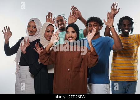 Eine jubelnde und vielfältige Gruppe, darunter ein Afroamerikaner und Hijab tragende Mädchen, winken und feiern überschwänglich und verkörpern die Lebendigkeit von Stockfoto