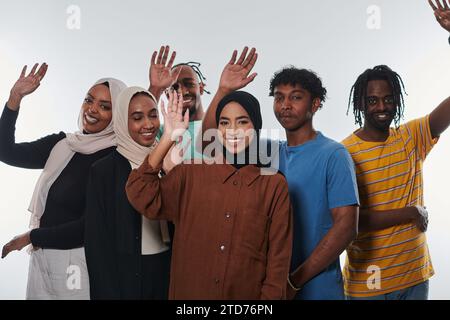 Eine jubelnde und vielfältige Gruppe, darunter ein Afroamerikaner und Hijab tragende Mädchen, winken und feiern überschwänglich und verkörpern die Lebendigkeit von Stockfoto