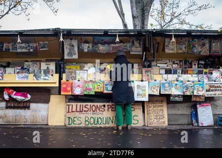 Paris, Frankreich. Dezember 2023. Eine Bouquiniste arbeitet an ihrem Stand. Bouquinistes, die berühmten Buchhändler von Paris, müssen während der Olympischen Spiele das seine-Ufer verlassen. Phrasen, die gegen diese Maßnahme protestierten, wurden an Buchhändlern verfasst. (Credit Image: © Telmo Pinto/SOPA Images via ZUMA Press Wire) NUR REDAKTIONELLE VERWENDUNG! Nicht für kommerzielle ZWECKE! Stockfoto