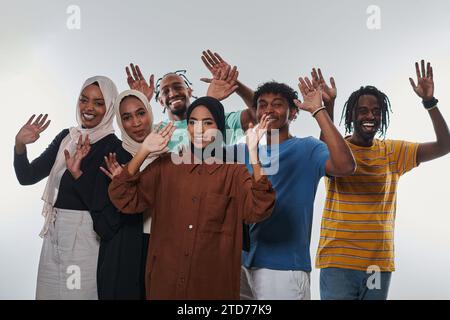 Eine jubelnde und vielfältige Gruppe, darunter ein Afroamerikaner und Hijab tragende Mädchen, winken und feiern überschwänglich und verkörpern die Lebendigkeit von Stockfoto