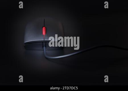 Schwarze Computermaus mit rotem Scrollrad, Nahaufnahme auf dunklem Hintergrund mit geringer Schärfentiefe Stockfoto