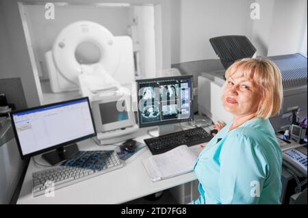 Medizinische Computertomographie oder MRT-Scanner. Porträt einer Krankenschwester, die am Computer arbeitet und ein MRT macht. Eine Frau in blauer Uniform. Konzept von Medizin und Krankenhaus. Stockfoto