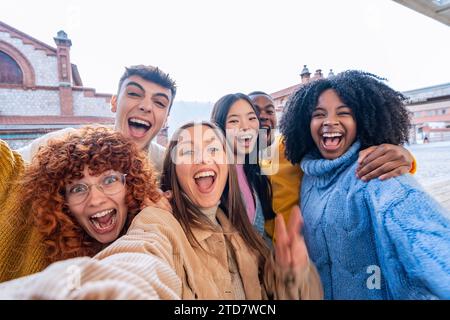 Junge glückliche multiethnische Freunde lächeln, während sie gemeinsam Selfies im Freien machen. Freundschaftskonzept. Stockfoto