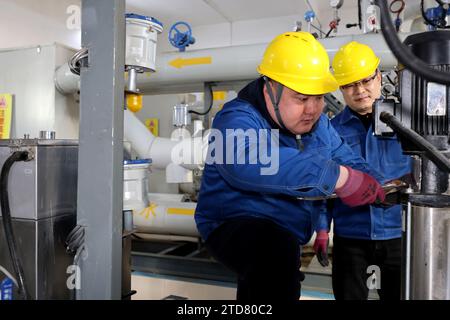 ZAOZHUANG, CHINA - 17. DEZEMBER 2023 - Mitarbeiter prüfen Heizgeräte an einer Wärmeaustauschstation in der Gemeinde Wantai Garden in der Stadt Zaozhuang, Stockfoto