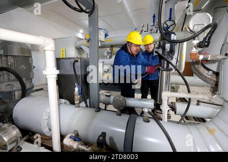 ZAOZHUANG, CHINA - 17. DEZEMBER 2023 - Mitarbeiter prüfen Heizgeräte an einer Wärmeaustauschstation in der Gemeinde Wantai Garden in der Stadt Zaozhuang, Stockfoto