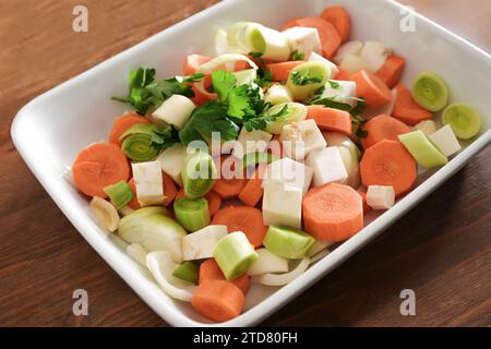 Französischer Mirepoix oder deutscher Suppengrun (Suppengrun), rohe Mischung aus gewürfeltem Gemüse mit Karotten, Lauch, Sellerie und Zwiebeln in einer weißen Schüssel, Basis für Sto Stockfoto