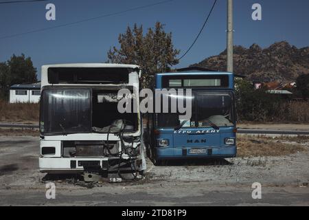 Verlassene und kaputte Busse am Stadtrand von Prilep in Nordmakedonien. Die Busse sind eindeutig unbrauchbar. Berge und blauer Himmel im Hintergrund. Stockfoto