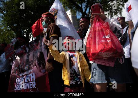 Während der Demonstration vor dem Gebäude der Vereinten Nationen in Bangkok winkt ein Kind mit einer Flagge. Birmanische Arbeiter in Thailand versammelten sich vor dem Gebäude der Vereinten Nationen, um den Tag der internationalen Migranten zu feiern und gegen die Entscheidung der Militärregierung in Myanmar zu protestieren, zusätzliche zwei Prozent als Lohnsteuer von ihren im Ausland arbeitenden Bürgern zu erheben. (Foto: Peerapon Boonyakiat / SOPA Images/SIPA USA) Stockfoto