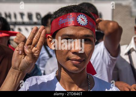 Während der Demonstration vor dem Gebäude der Vereinten Nationen in Bangkok grüßt ein Demonstrant mit drei Fingern. Birmanische Arbeiter in Thailand versammelten sich vor dem Gebäude der Vereinten Nationen, um den Tag der internationalen Migranten zu feiern und gegen die Entscheidung der Militärregierung in Myanmar zu protestieren, zusätzliche zwei Prozent als Lohnsteuer von ihren im Ausland arbeitenden Bürgern zu erheben. (Foto: Peerapon Boonyakiat / SOPA Images/SIPA USA) Stockfoto