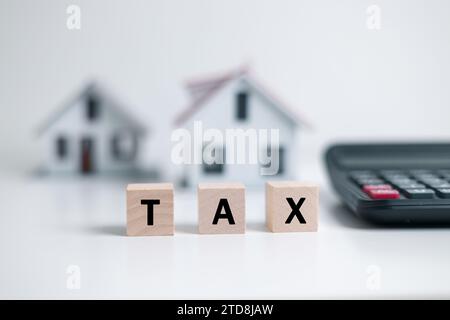 Konzept der Zahlung der staatlichen Grundsteuer. Grundsteuer Holzblöcke mit Miniaturhaus. Hausmodell, Hypotheken beladen Immobilien mit Darlehen Stockfoto