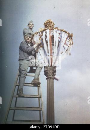 Paris, Frankreich zwei Soldaten, die einen Lampenträger für die Feierlichkeiten zum Siegestag vom 13. Und 14. Juli 1919 dekorieren, Kleidung, Party, HD, erster Weltkrieg, Menschen, Gesellschaft, Lampenpfosten, Straßenlaterne, Militäruniform, politische Partei, existiert in hoher Auflösung, Gedenkfeier, Nachkriegszeit, Mann, Armee, Frankreich, Paris, ohne Bildunterschrift, Paris, 01.07/1919 - 31.07.1919, Cuville, Fernand, Autochrome, Foto, Glas, Autochrome, Foto, positiv, Vertikal, Größe 9 x 12 cm Stockfoto