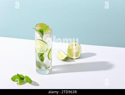 Eis und Mojito im Glas liegen mit starkem Schatten auf dem Tisch Stockfoto