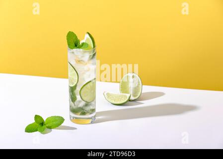 Eis und Mojito im Glas liegen mit starkem Schatten auf dem Tisch Stockfoto