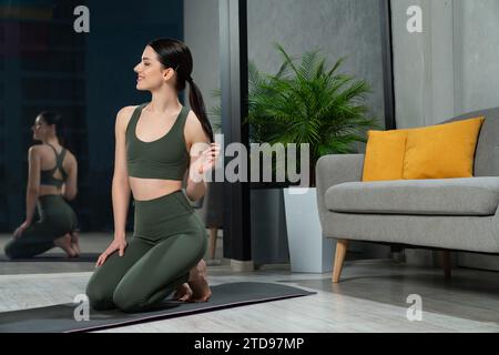Lächelnde Frau auf Yogamatte in einem gemütlichen Zimmer. Stockfoto