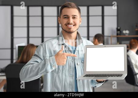 Männlicher Programmierer, der auf leeren Laptop im Büro zeigt Stockfoto