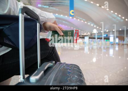 Eine Frau sitzt und wartet, nachdem sie die Ticketausstellung am Flughafen abgeschlossen hat Stockfoto