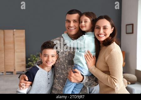 Soldat mit seiner Frau und kleinen Kindern, die sich zu Hause umarmen Stockfoto