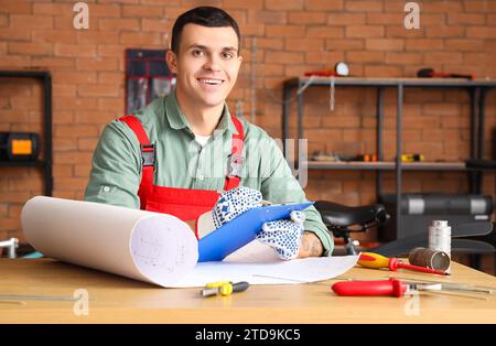 Fahrradmechaniker, der mit Klemmbrett am Tisch in der Werkstatt arbeitet Stockfoto