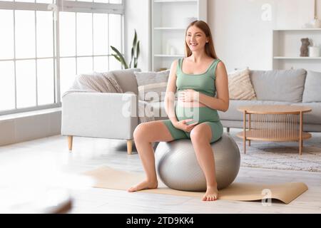 Sportliche junge schwangere Frau, die zu Hause auf dem Fitball trainiert Stockfoto