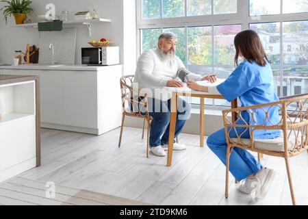 Die Blutdruckmessung des reiferen Mannes in der Küche Stockfoto